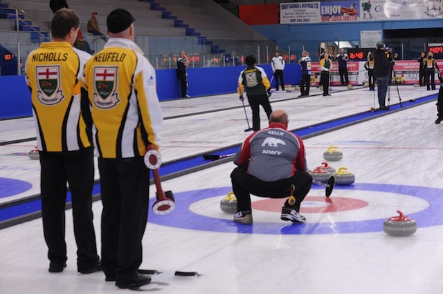 Manitoba’s Randy Neufeld and Peter Nicholls watch as Northwest Territories’ Brian Kelln calls the line (Curling Canada/Mike Lewis photo)